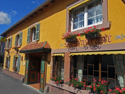 a yellow building with flower boxes and windows at Maison de Laveline in Laveline