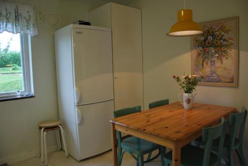 a kitchen with a wooden table and a refrigerator at Peterslund in Östra Tommarp