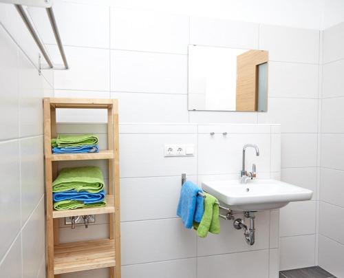 a bathroom with a sink and a shelf with towels at Krug-Apartments in Ebelsbach