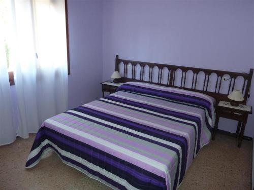 a bedroom with a bed with a striped blanket on it at Villa rustical 14 in Montroig