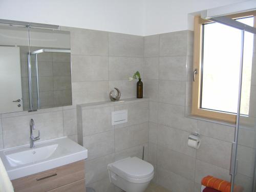 a bathroom with a sink and a toilet and a window at Apartmenthaus STYRIA in Bad Gleichenberg