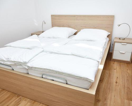 Una cama con sábanas blancas y almohadas. en Krug-Apartments, en Ebelsbach