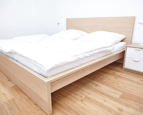 a bed with white sheets and a wooden frame in a room at Krug-Apartments in Ebelsbach