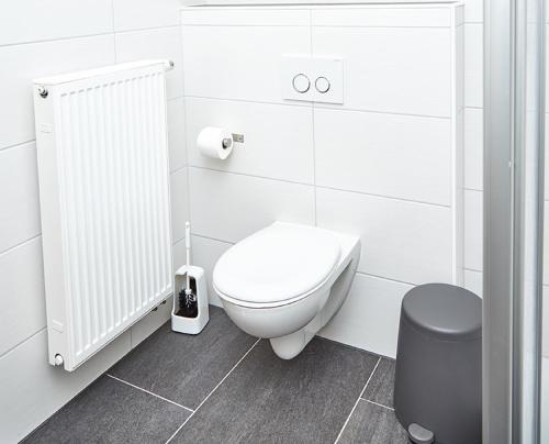 a white bathroom with a toilet and a trash can at Krug-Apartments in Ebelsbach