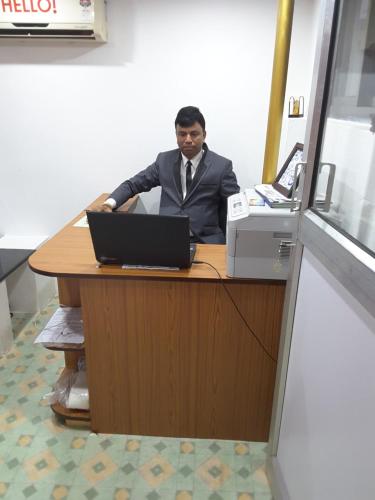 mężczyzna siedzący przy biurku z laptopem w obiekcie Minria Guest House w mieście Benaulim