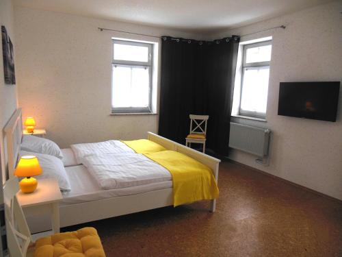 a bedroom with a bed with a yellow blanket and two windows at FeWo Hottelstedt in Hottelstedt