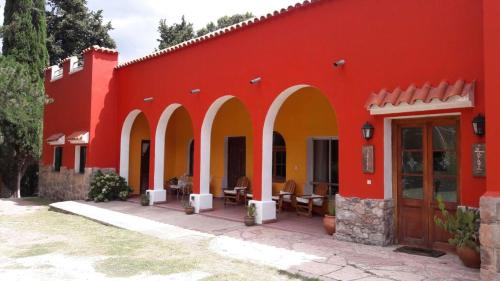 a red building with arches and tables and chairs at Hotel Zapata in La Cumbre