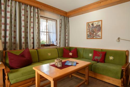 a living room with a green couch and a table at Alpasella Ferienwohnungen in Sankt Gallenkirch