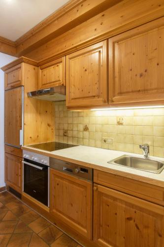 a kitchen with wooden cabinets and a sink at Alpasella Ferienwohnungen in Sankt Gallenkirch