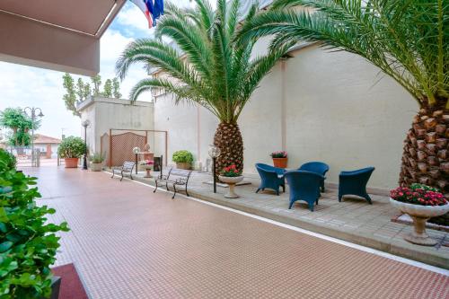 a courtyard with palm trees and blue chairs at Le Terrazze in Follonica