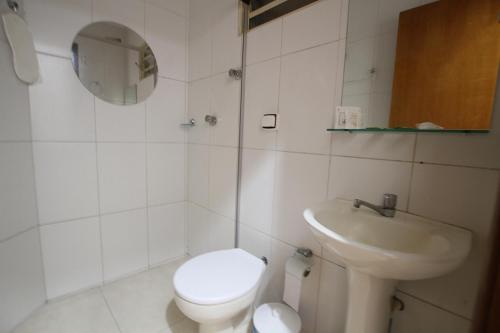 Baño blanco con aseo y lavamanos en Hotel Friburgo, en Cidade Ocidental