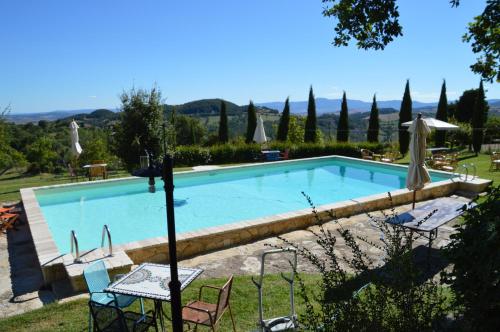 a large swimming pool with two chairs and an umbrella at Il Borgo Del Lupo Relax Family Apartments in Tuscany with Restaurant & Swimming Pool in Sarteano