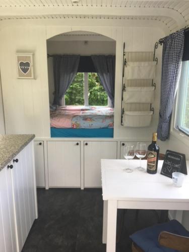 a kitchen with a table and a room with a bed at Shepherds hut (Pipowagen) in Oostvoorne