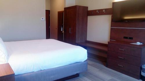 a bedroom with a white bed and a dresser and a television at Route 66 inn & Suites in Miami