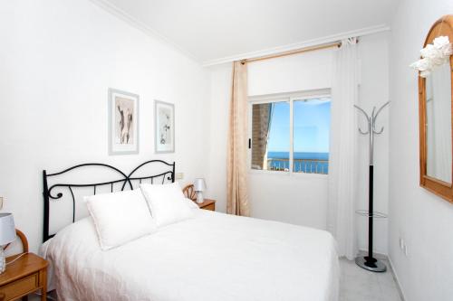 アレナレス・デル・ソルにあるApartamento Balcón del Marの白いベッドルーム(ベッド1台、窓付)