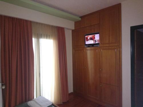 a bedroom with a window and a dresser with a television at Elikonio in Agia Anna