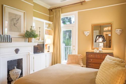 a bedroom with a fireplace and a bed and a mirror at Catherine Ward House Inn in Savannah