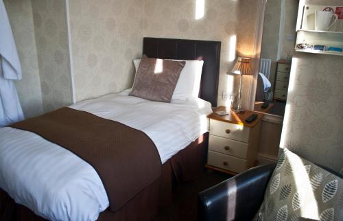 a bedroom with a bed and a nightstand with a lamp at Woodthorpe Hotel in Skegness