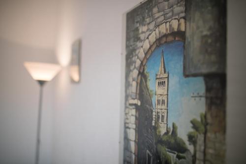 a painting of a church on a wall next to a lamp at Apartments Dania in Lopar