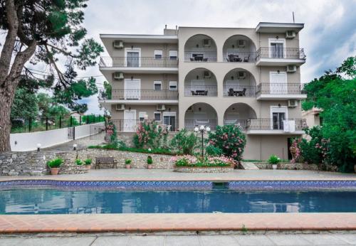 un immeuble d'appartements avec une piscine en face dans l'établissement Villa Albanis, à Kolios