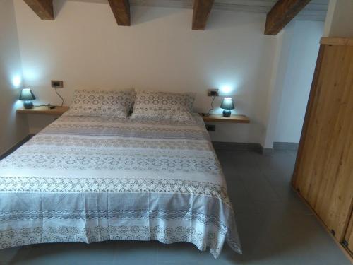 a bedroom with a bed and two lamps on two tables at Appartamento Sole in Morgex