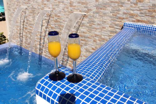 two glasses of orange juice on a table next to a swimming pool at Vallarta Shores Beach Hotel in Puerto Vallarta