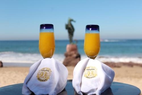 two glasses of beer sitting on a table at the beach at Vallarta Shores Beach Hotel in Puerto Vallarta