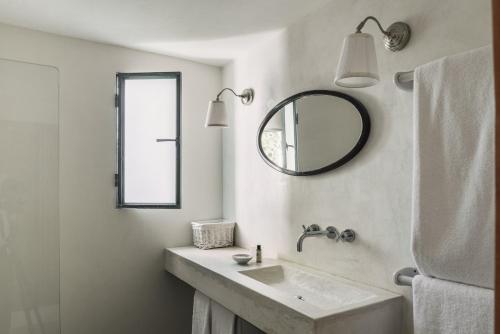 a white bathroom with a sink and a mirror at Tres Marias in Vila Nova de Milfontes