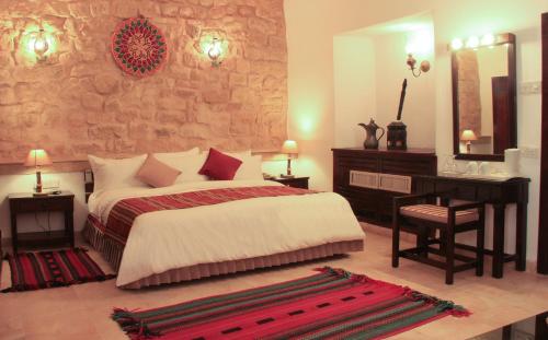 a bedroom with a bed and a desk and a mirror at Hayat Zaman Hotel And Resort Petra in Wadi Musa