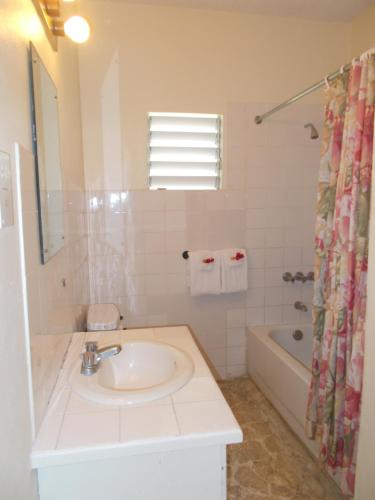 a white bathroom with a sink and a bath tub at Paradise Inn in Port Antonio