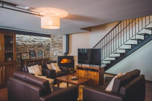 a living room with couches and a tv and a staircase at Casa da Obrinha in Bouro