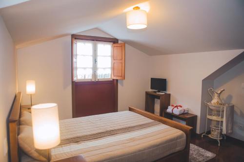 a bedroom with a bed with two lights and a window at Casa da Obrinha in Bouro