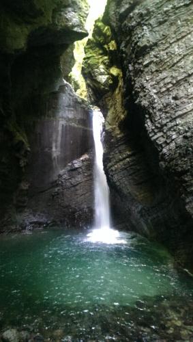 a waterfall in a cave with a pool of water at Apartments Hlapi with SPA in Kobarid