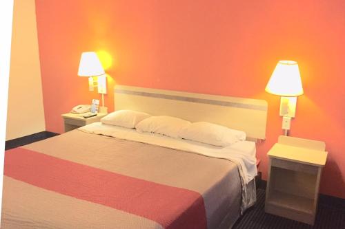 a hotel room with a bed with two tables and two lamps at Red Carpet Inn in Gibbstown