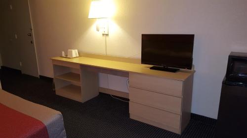 a desk with a television on it in a hotel room at Red Carpet Inn in Gibbstown