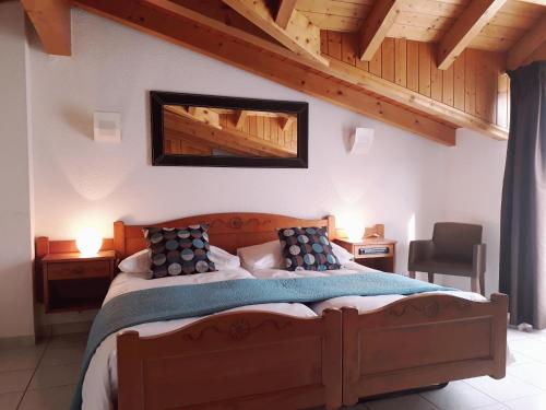 ein Schlafzimmer mit einem großen Bett in einem Zimmer mit Holzdecken in der Unterkunft Hôtel de Fully in Fully