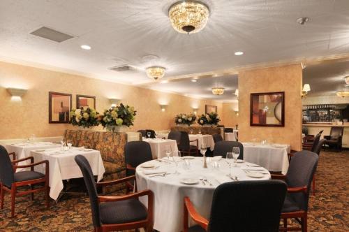 a dining room with tables and chairs with white tablecloths at The Senator Hotel & Conference Center Timmins in Timmins