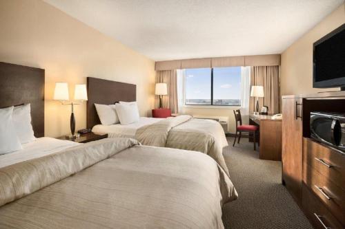 a hotel room with two beds and a television at The Senator Hotel & Conference Center Timmins in Timmins