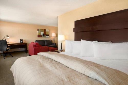 a hotel room with a large bed and a desk at The Senator Hotel & Conference Center Timmins in Timmins