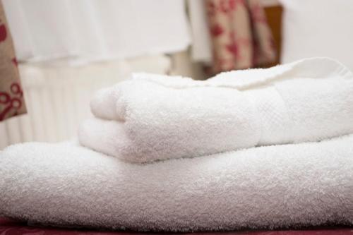a white towel sitting on top of a white towel covered bed at Brunel Hotel in London
