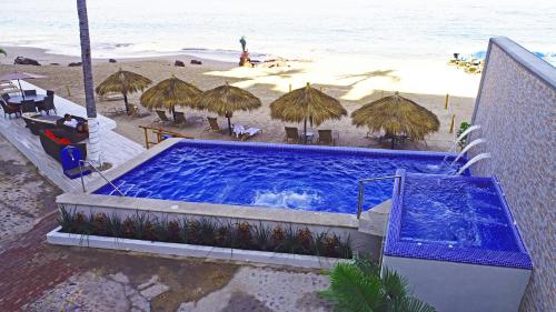 a large swimming pool next to a beach with umbrellas at Vallarta Shores Beach Hotel in Puerto Vallarta