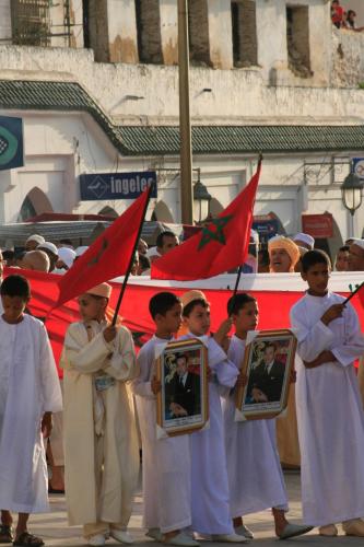 a group of children holding flags and pictures in a parade at Dar Zerhoune in Moulay Idriss Zerhoun