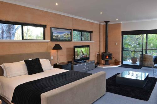 a bedroom with a large bed and a tv in it at Aroha in Margaret River Town