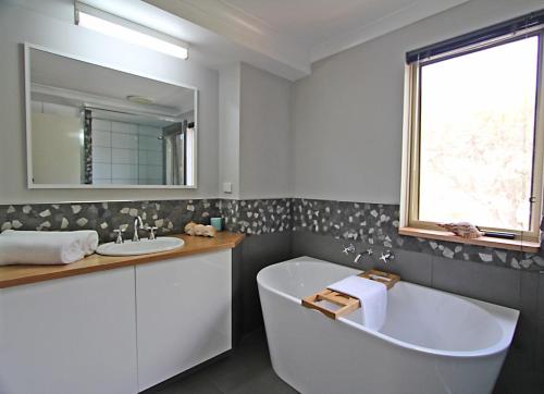 a bathroom with a tub and a sink and a mirror at Stones-Throw in Margaret River Town