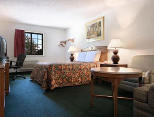 Habitación de hotel con cama, mesa y sofá en Travelodge by Wyndham Waukegan Gurnee, en Waukegan