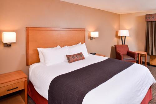 a hotel room with a large bed and a chair at Best Western Plus Olympic Inn in Klamath Falls