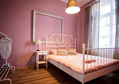 ein rosafarbenes Schlafzimmer mit einem weißen Bett und einem Spiegel in der Unterkunft Apartamenty Nowy Rynek in Bydgoszcz