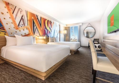 a hotel room with two beds and a mirror at The LINQ Hotel and Casino in Las Vegas