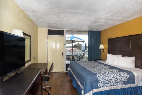 a hotel room with a bed and a flat screen tv at Days Inn & Suites by Wyndham Port Richey in Port Richey