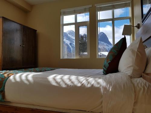 Sunset Resorts Canmore and Spa في كانمور: غرفة نوم بسرير مطل على الجبال